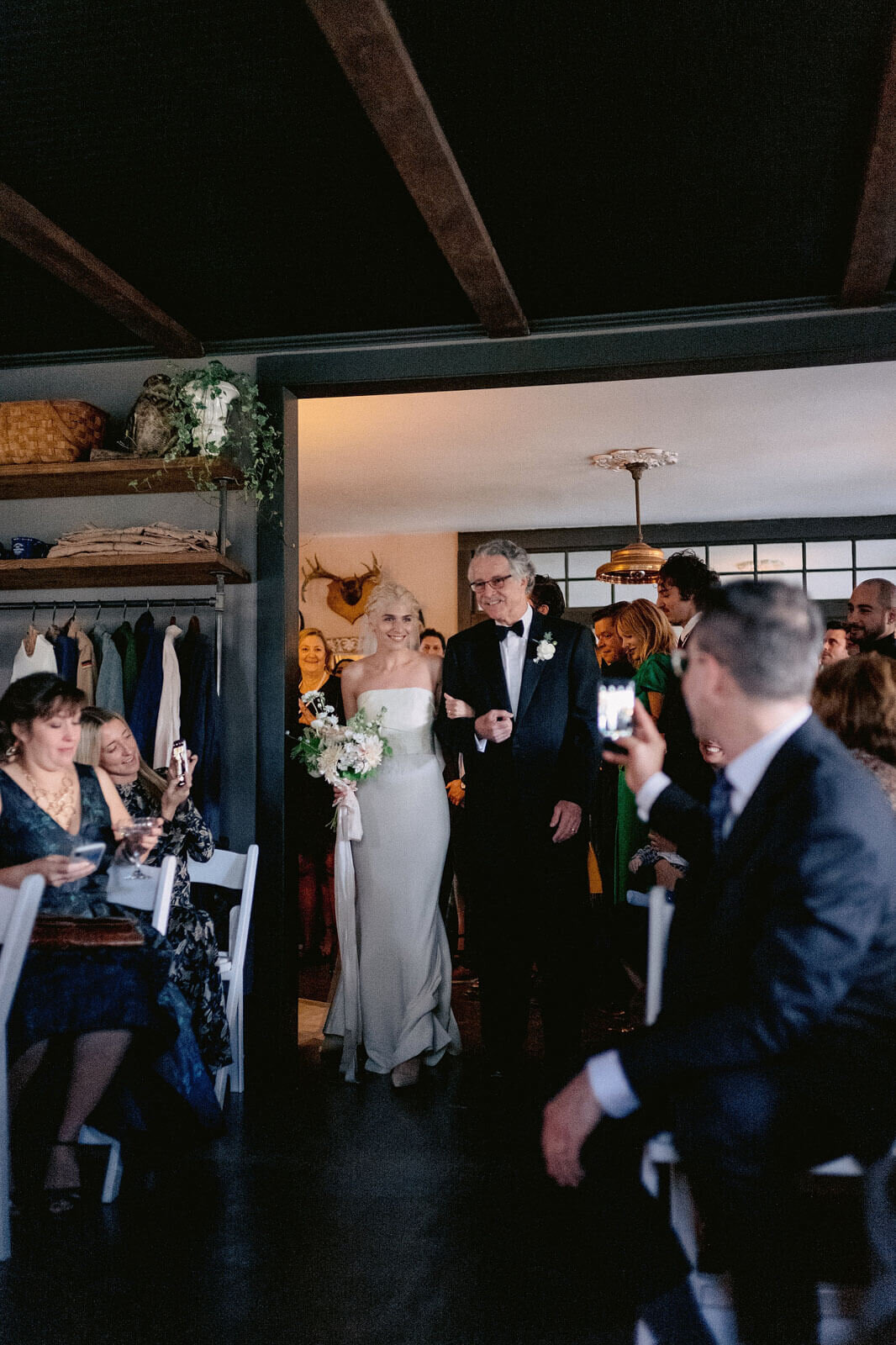 The bride and her father start to walk down the aisle in Foxfire Mountain House, New York. Wedding Image by Jenny Fu Studio