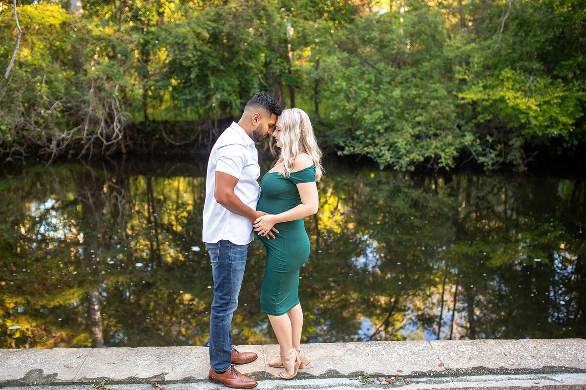 Woman and man stand next to Hillsborough River in morning light  forehead to forehead