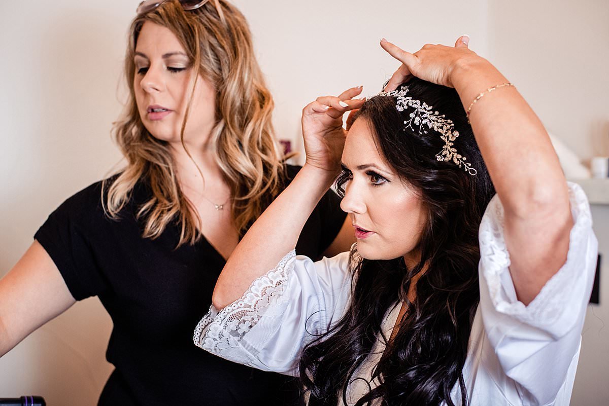Bride and hair dresser adjusting the crystal hairpiece in her wedding hairdo
