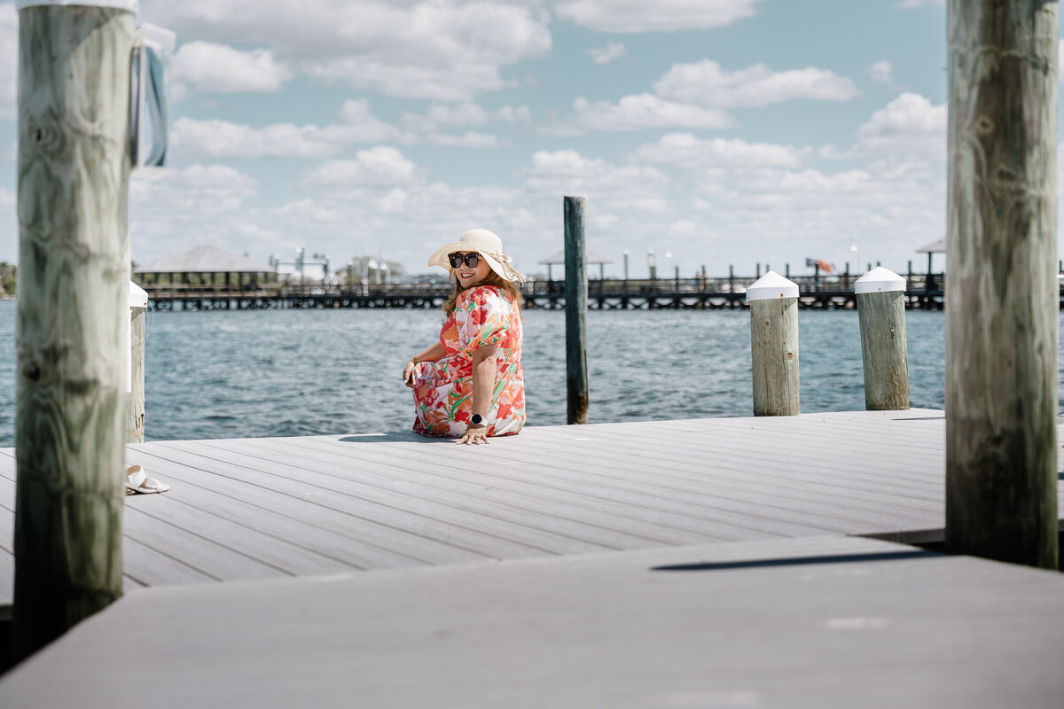 A woman sitting at the edge of the pier of a beach house, celebrating birthday, but posed portrait, natural light photography