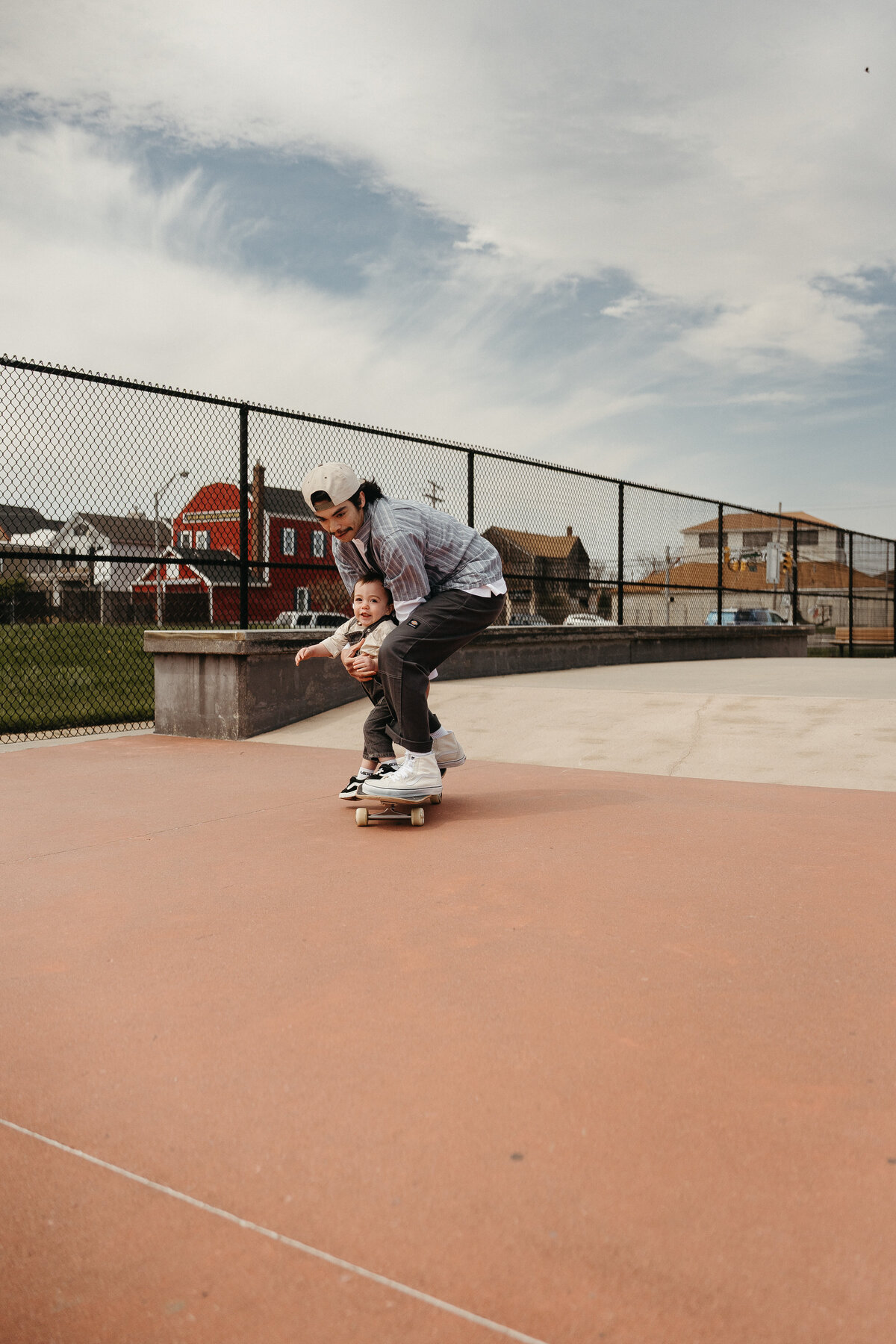 Dad and son riding on a skateboard in a skatepark