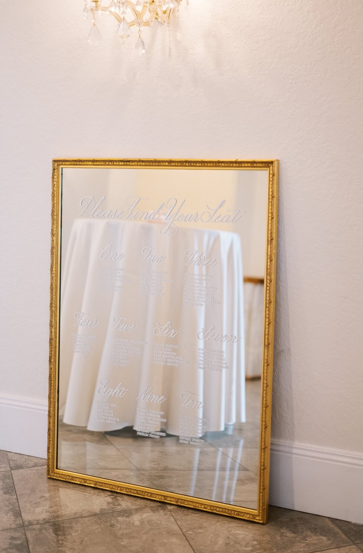 Large gold mirror with ornate border with calligraphy for seating chart