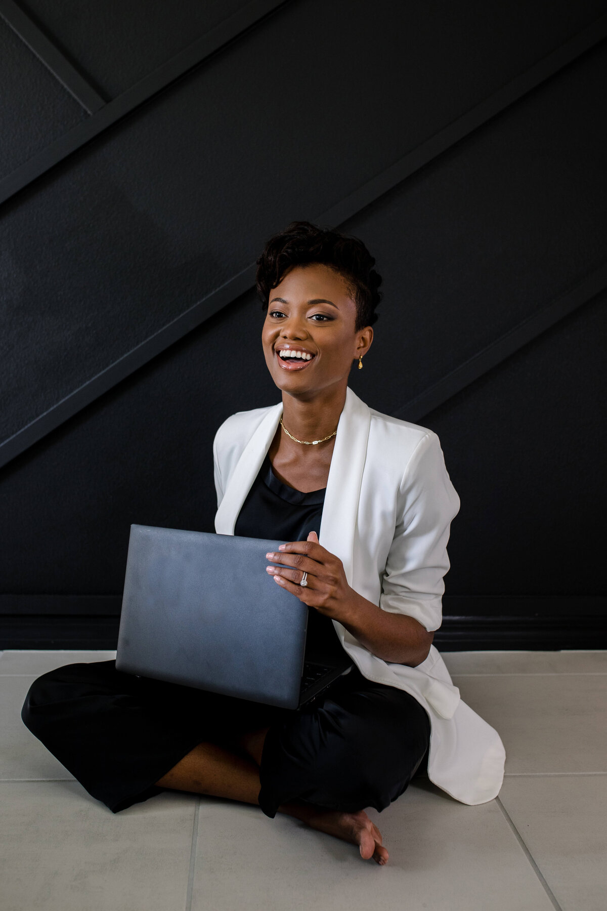 Branding photo shoot with candid brand photo of women laughing as she works on her desk pop while sitting down with a black background