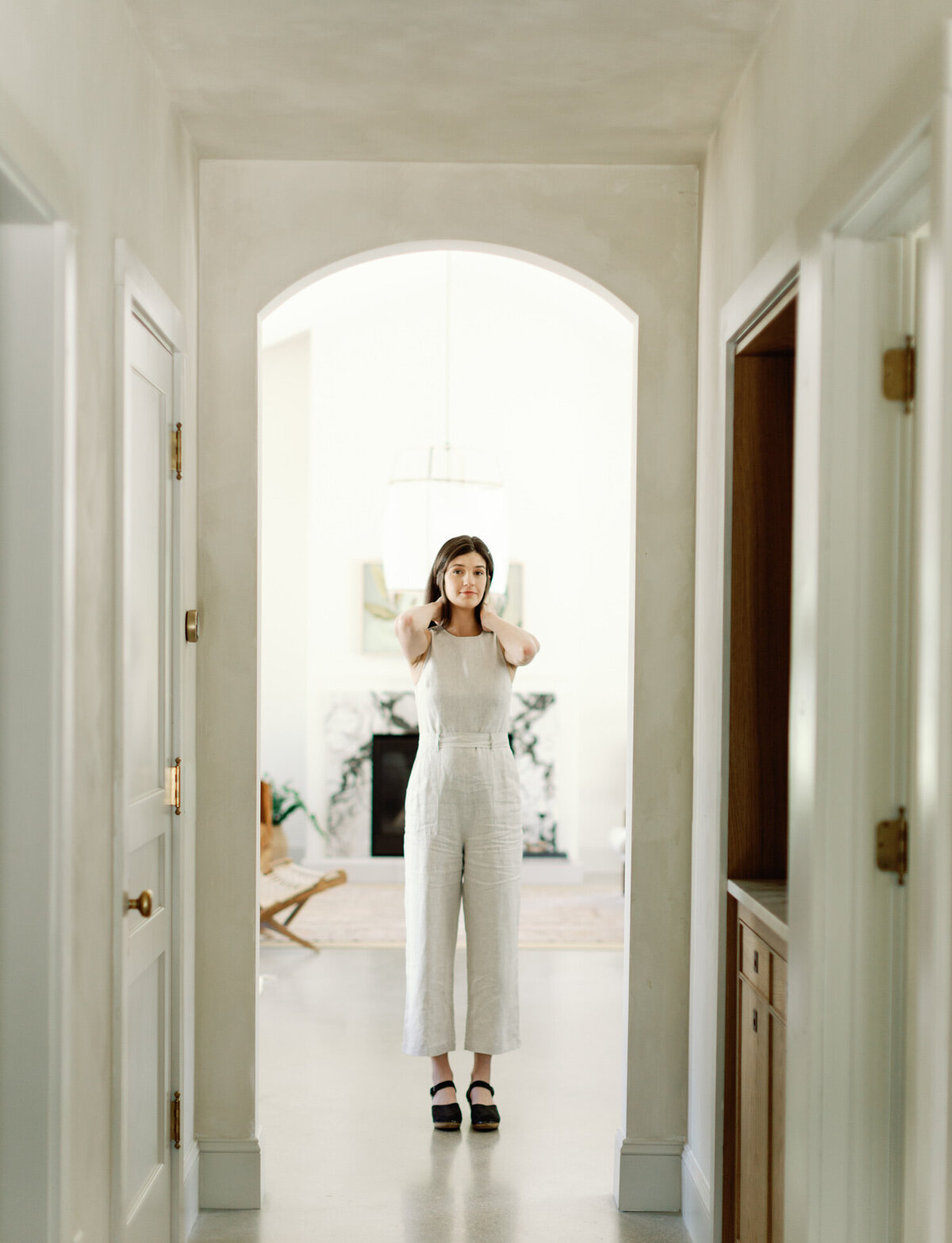 a designer in beige linen jumpsuit under design arch at Fernhaus, a Northern Michigan film branding photoshoot
