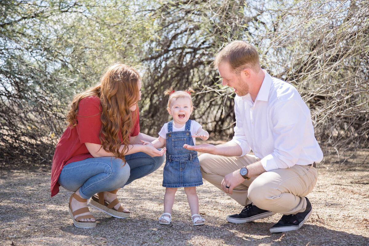 Couple in a desert park  playing with happy toddler in denim dress