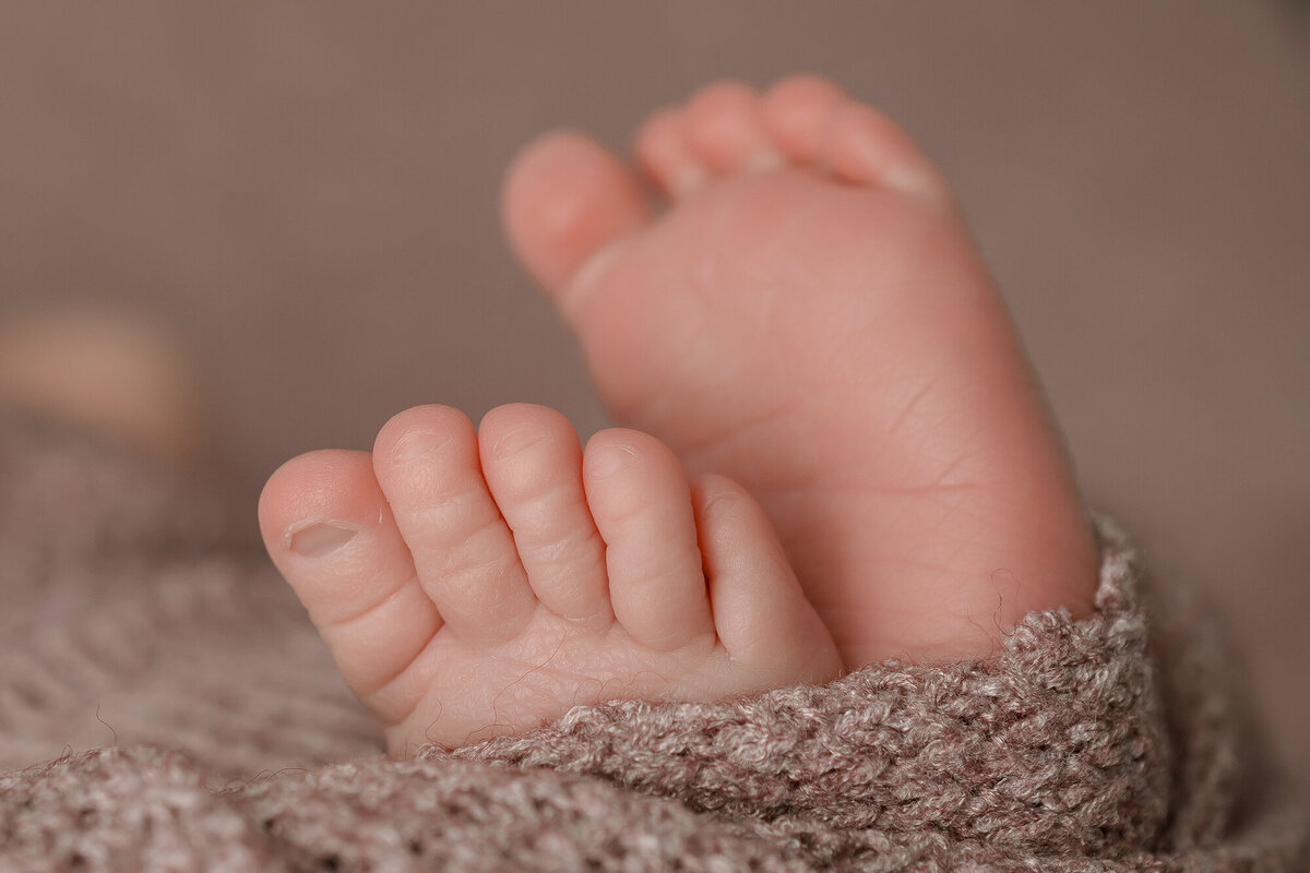 Details of a newborn's feet in knit swaddle