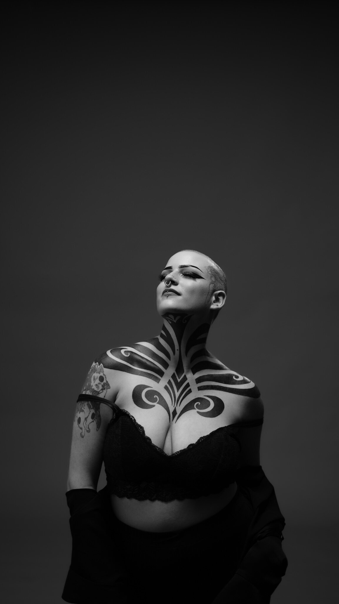 Black and white image of a tattooed woman in a portrait studio