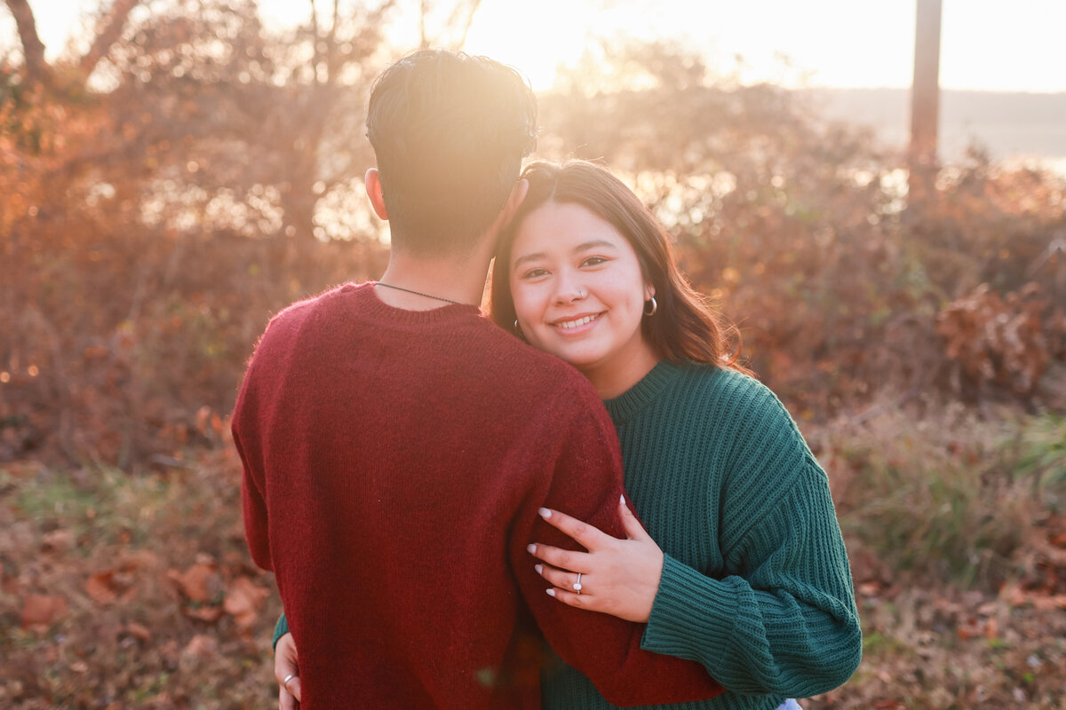 man wearing red sweater giving his fiance a hug on the side and shes wearing a green sweater