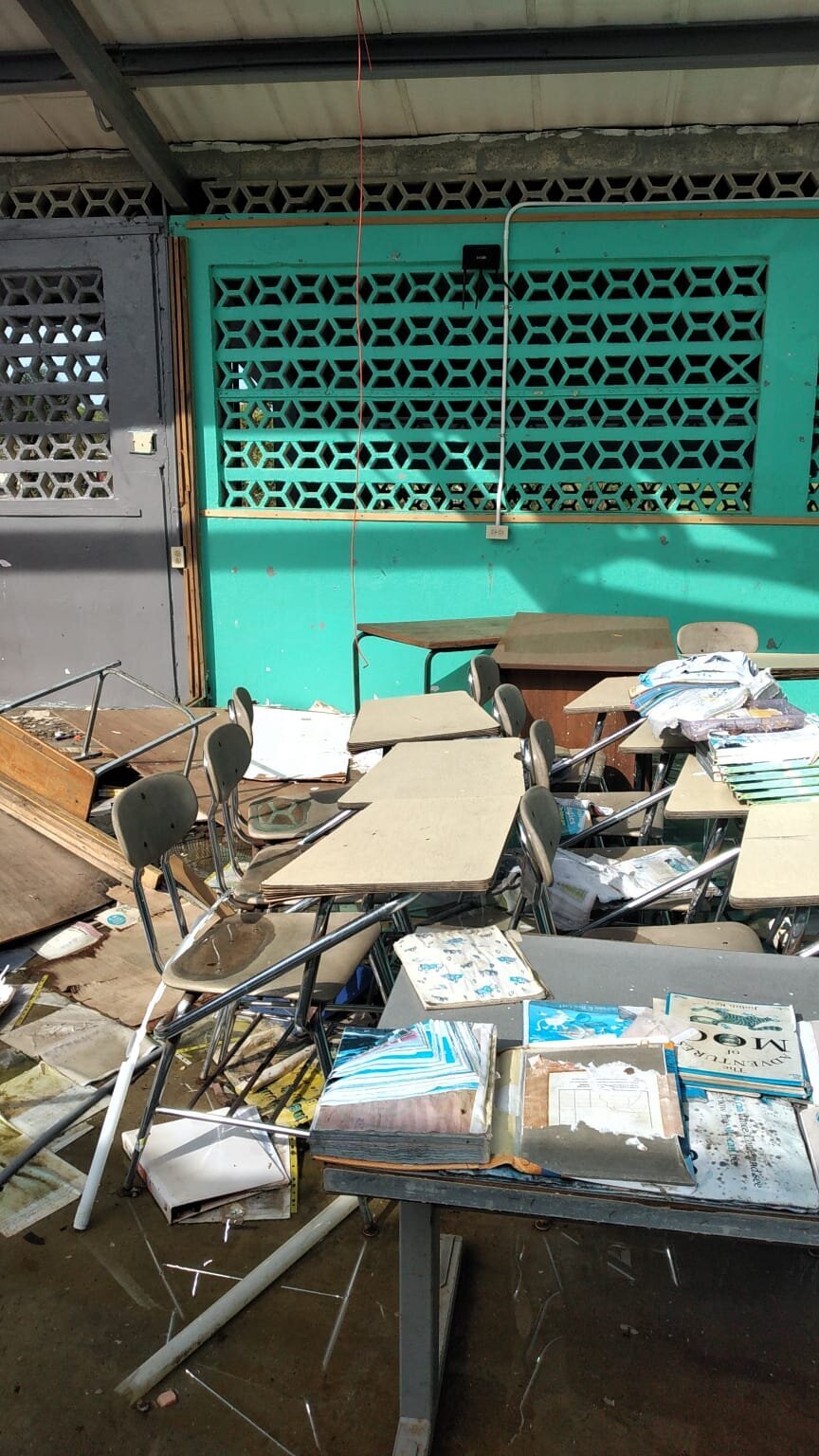 Debris and broken classroom materials piled across the room after storm damage
