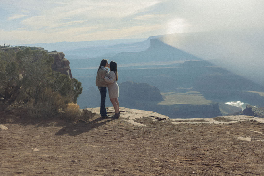 A couple kissing on a canyon overlook.