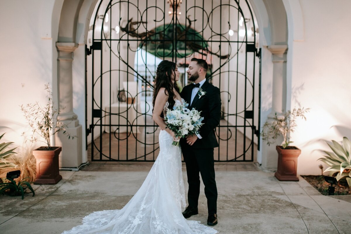 Bride and Groom looking at one another lovingly outside of the iron gates in their Laguna Beach wedding venue.