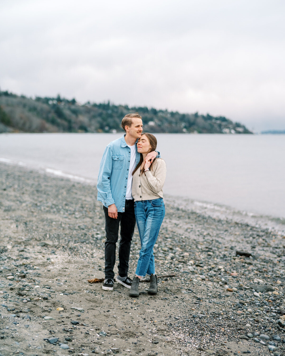 Couple stands on a lakeside beach