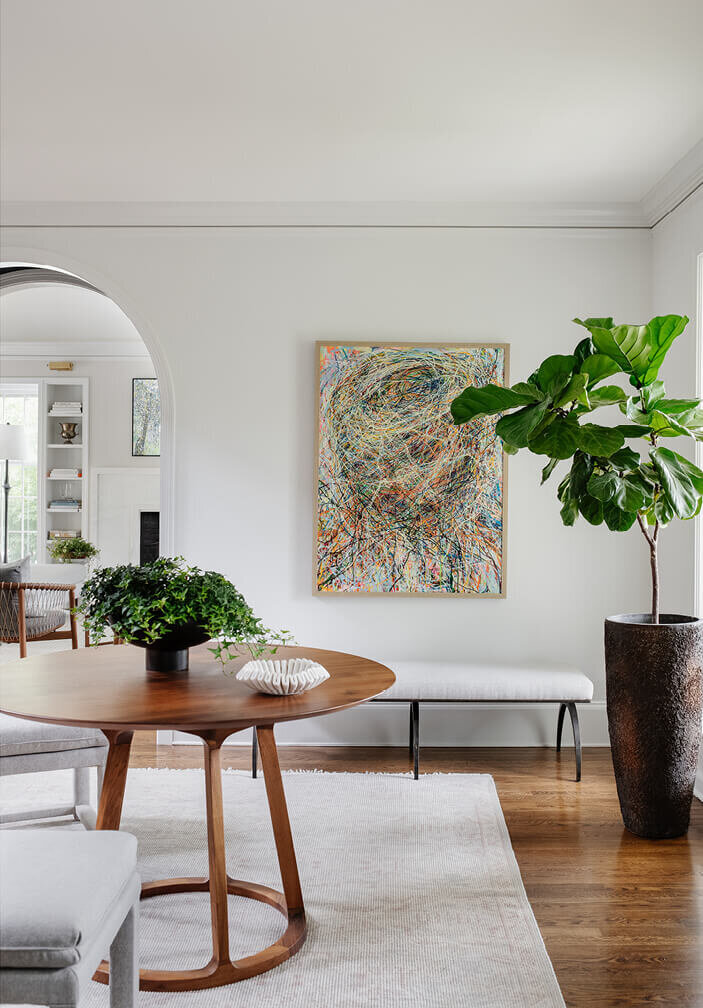 Historic home design foyer with modern furniture and fun art by a Hingham interior decorator, blending contemporary style with classic architectural elements.