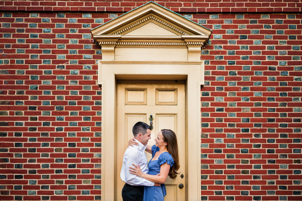 Man, a woman, hugging in front of a yellow door, surrounded by red bricks, and Philadelphia PA