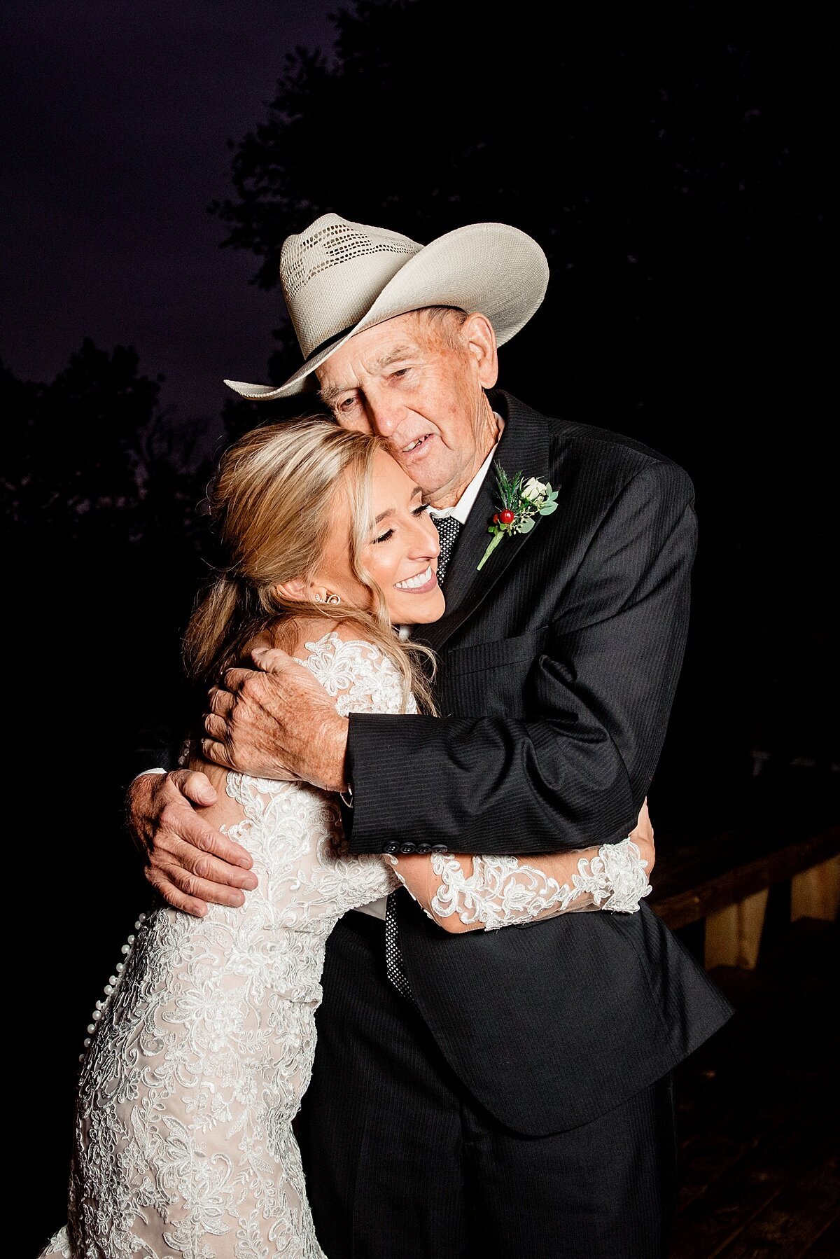 bride in lace dress hugging groom in cowboy hat