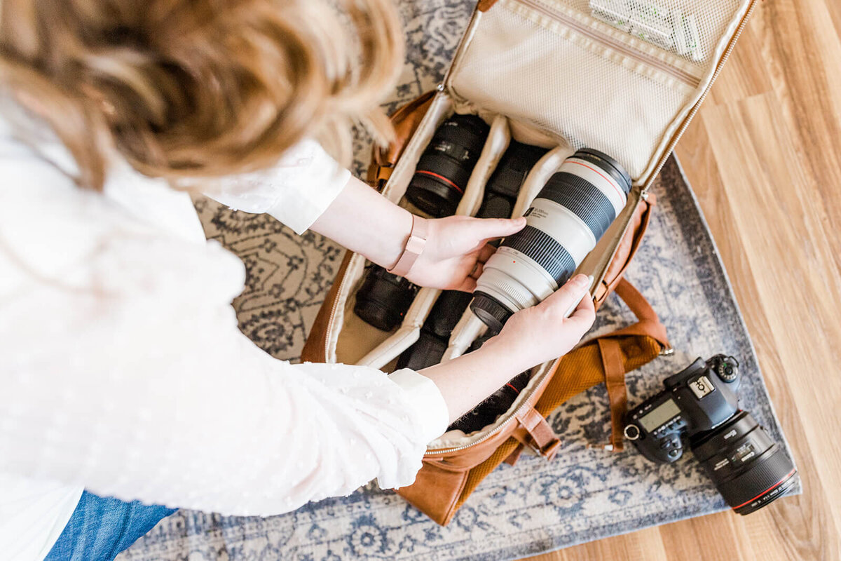 Photographer putting away camera lenses in brown bag