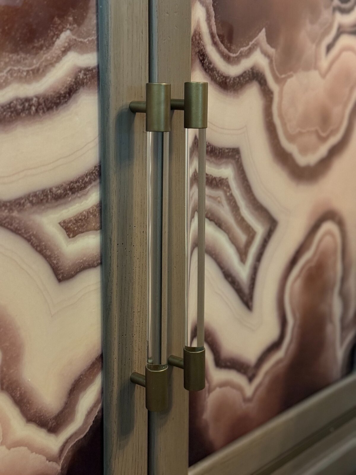 Close-up of a luxury agate-front bar cabinet with crystal glassware and fresh floral arrangement in a Phoenix home.