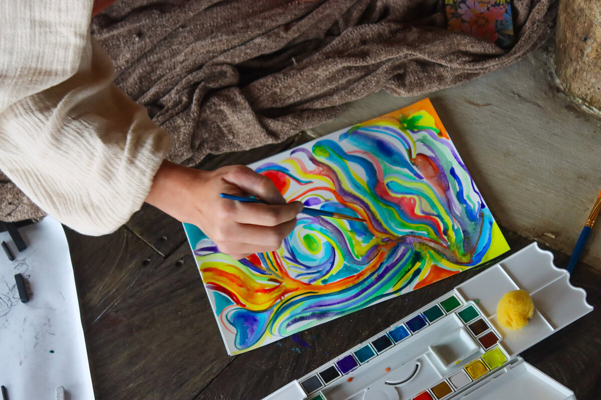 Overhead view of a woman painting colorful abstract art, an example of Courtney's retreat photography