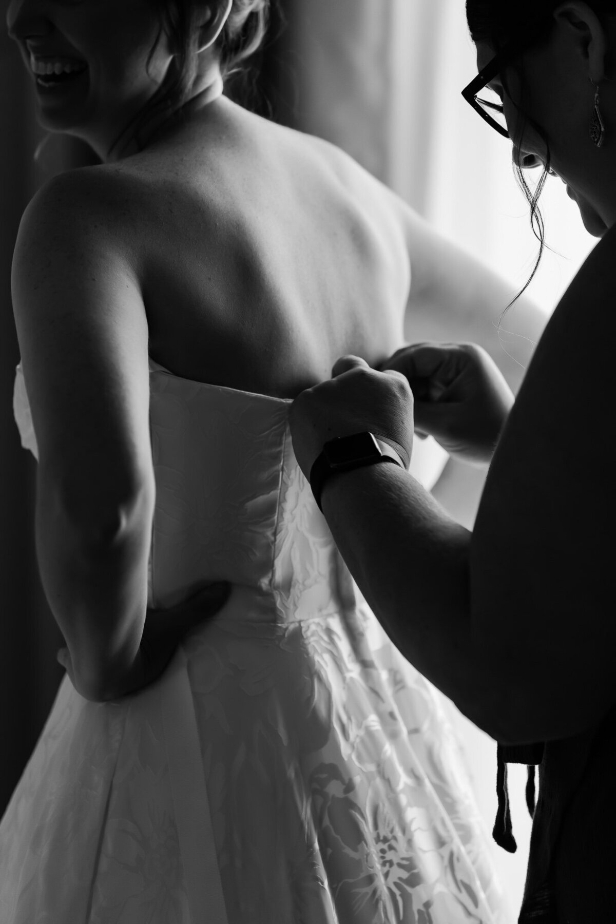 Bride's wedding dress being zipped by her sister