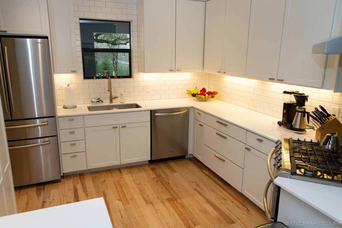 white kitchen with stainless steel appliances. silver appliances in modern kitchen with hardwood floors.