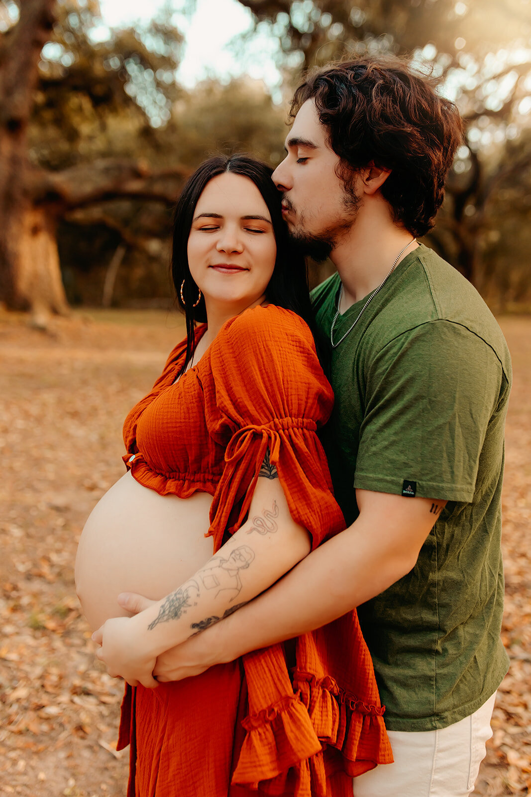 Maternity session in Cleveland TX with couple embracing outdoors, husband kissing wife’s forehead