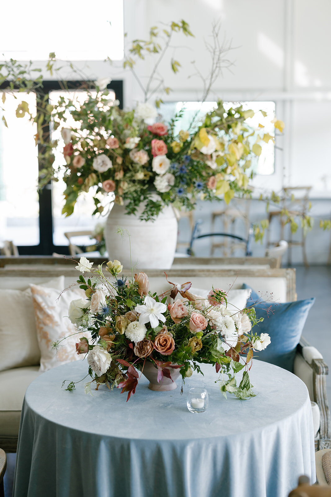 Large cocktail hour urn floral statement arrangement for fall Carolina’s wedding in Raleigh. Floral colors in mauve, cream, dusty pink, dusty blue, copper, and natural green. Floral accents of roses and fall color branches. Design by Rosemary and Finch Floral Design based out of Nashville, TN. 