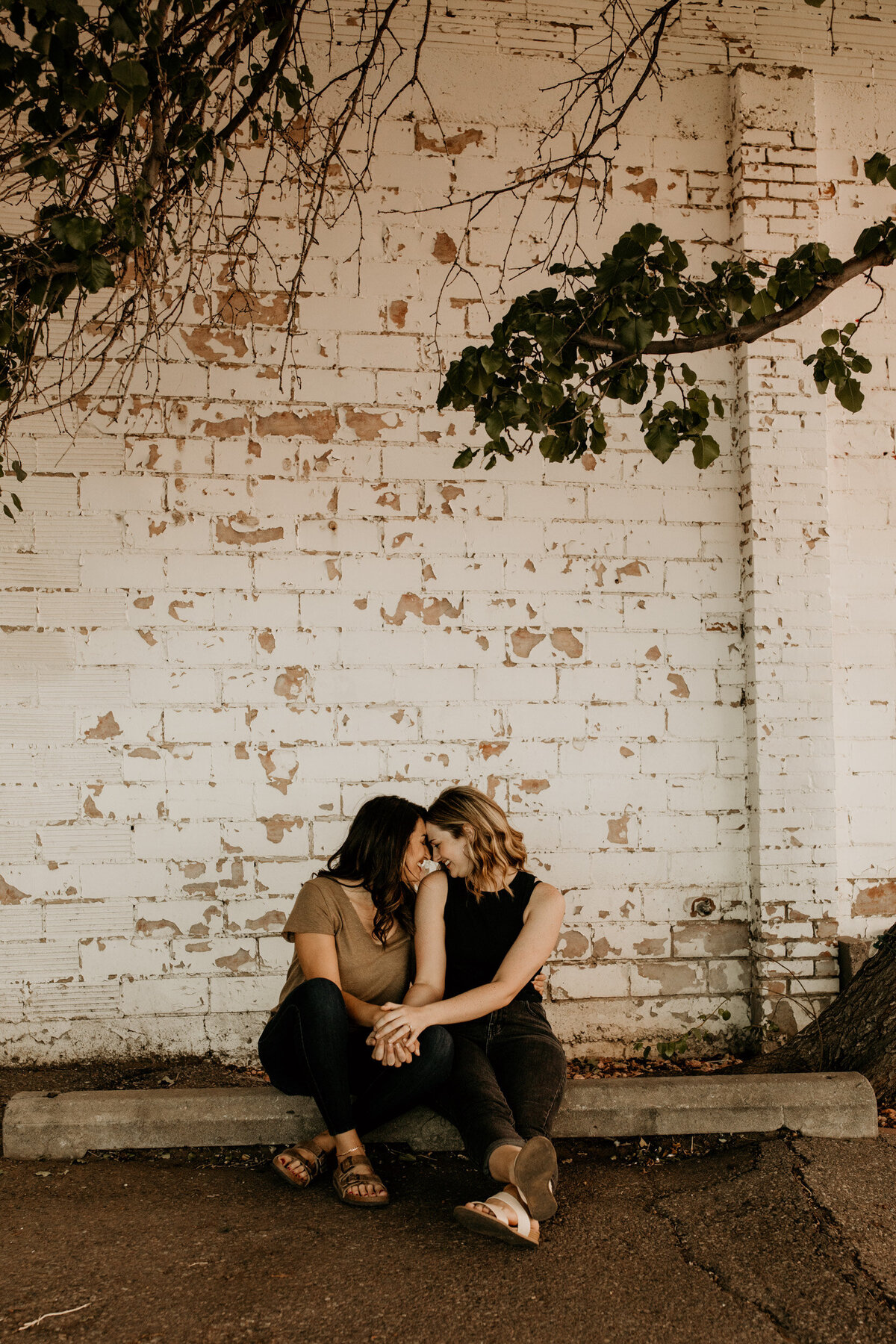 same sex couple sitting together under a tree