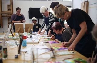 Adults working on ink artwork in workshop