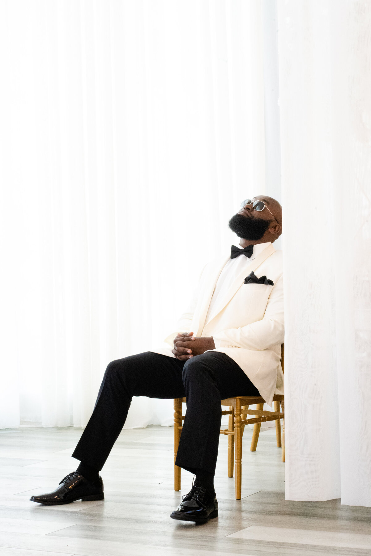 Black groom sitting in chair staring at the ceiling