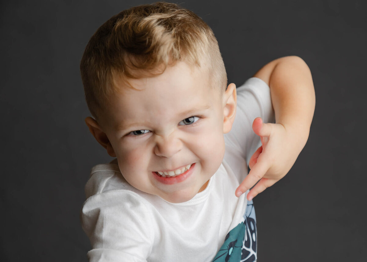 Funny school picture of a preschool aged white boy on a gray backdrop in Las Vegas, NV
