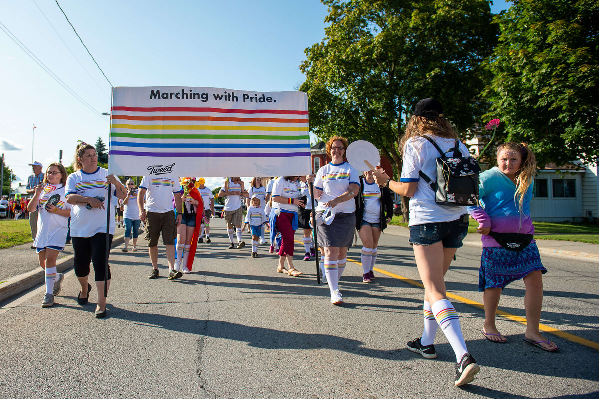 Marchers in a pride parade carrying a colourful sign.  Captured by Ottawa Event Photographer JEMMAN Photography COMMERCIAL during the Tweed Canopy Growth Pride Parade
