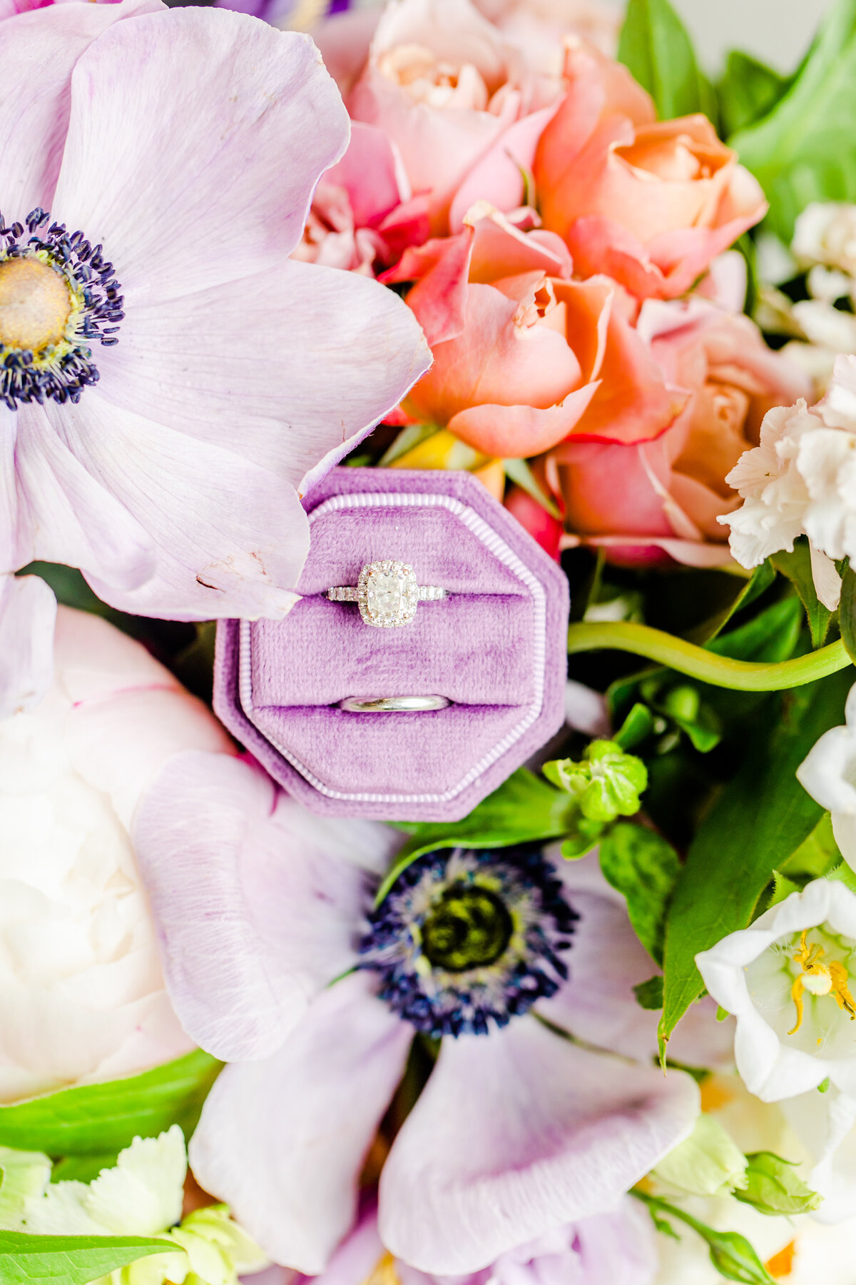 photo of wedding rings and engagement ring with purple anemones