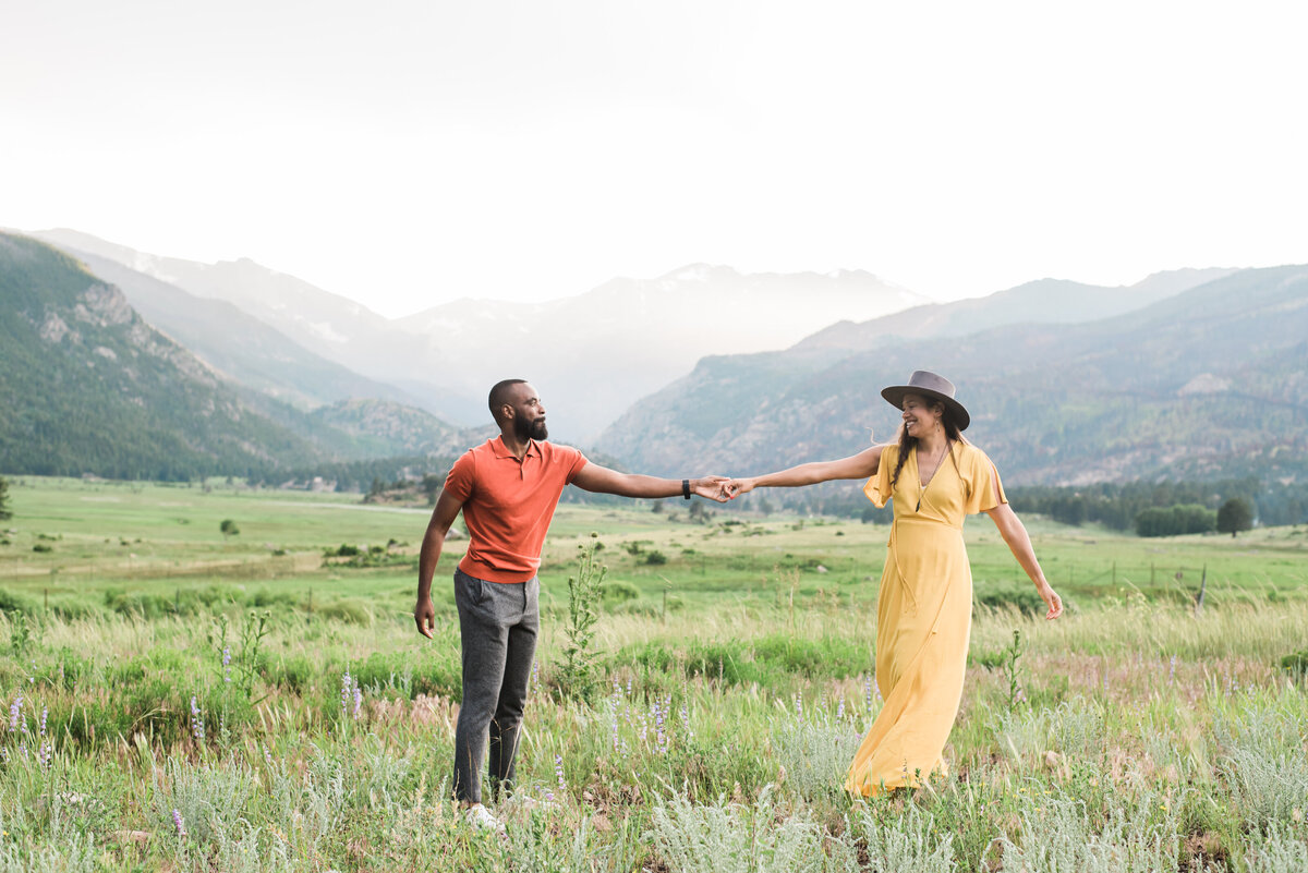 A man in an orange top and a woman in a bright yellow dress both dance together while colorado wedding photographer KB Radiant Photography captures the moment in Rocky mountain national park
