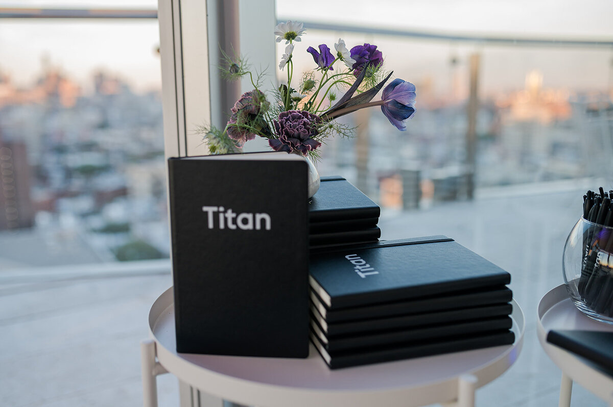 Titan-branded notebooks styled with floral accents at Titan Day in New York, produced to create a cohesive and polished corporate event environment.