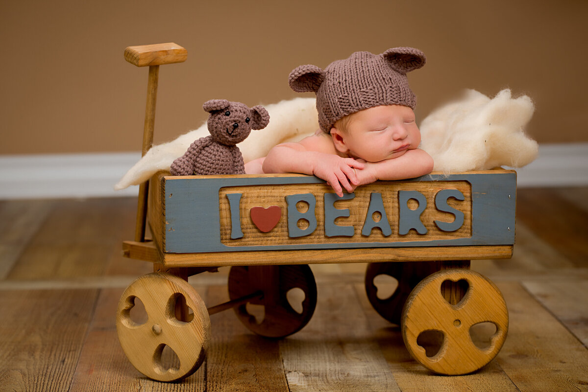 Newborn posed in a vintage toy train with the word 'LOLA' on the side, captured in Overland Park, Kansas. A playful and creative option for families looking for unique newborn photography themes.