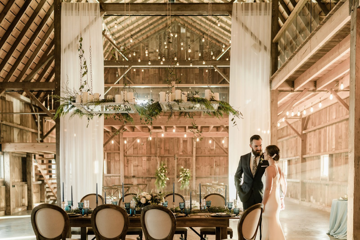 Bride and Groom standing inside their elegant reception at Countryside Barn, rustic, country Lethbridge, Alberta wedding venue, featured on the Brontë Bride Vendor Guide.
