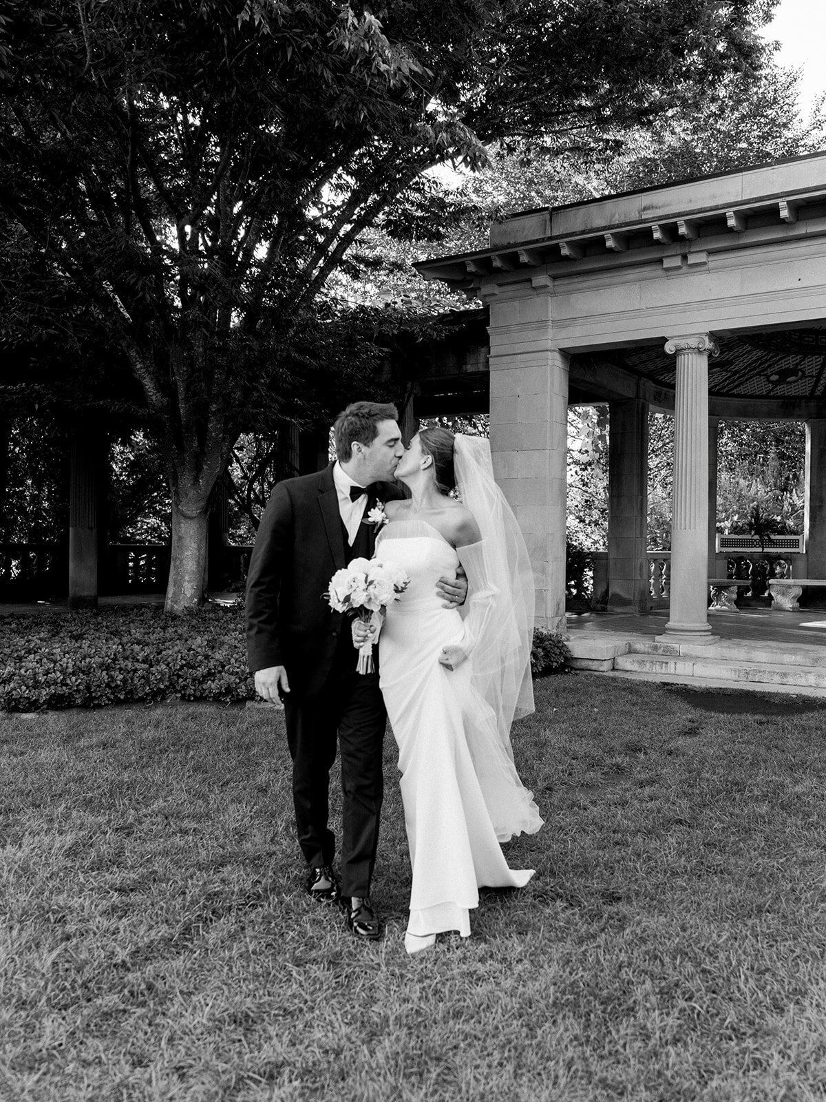 bride and groom kiss during their portraits in the garden at Eolia Mansion