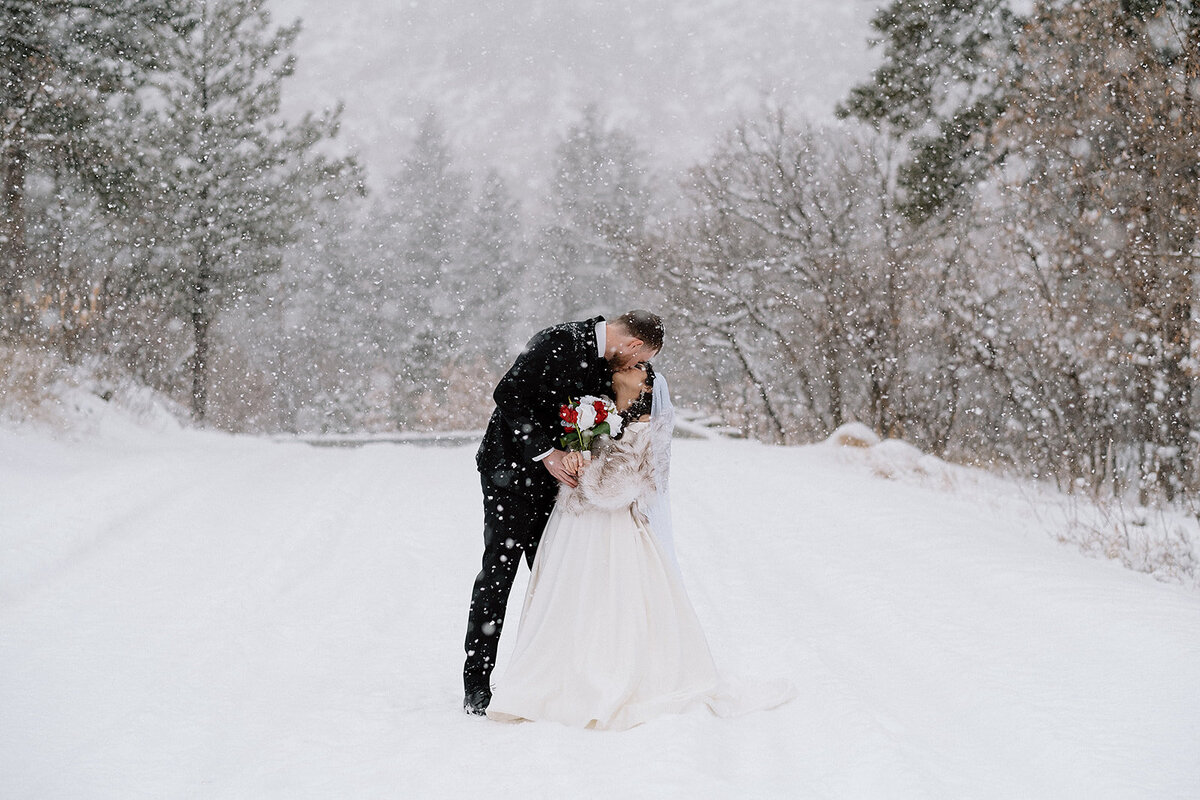 bride and groom kiss in the snow on wedding day in Colorado