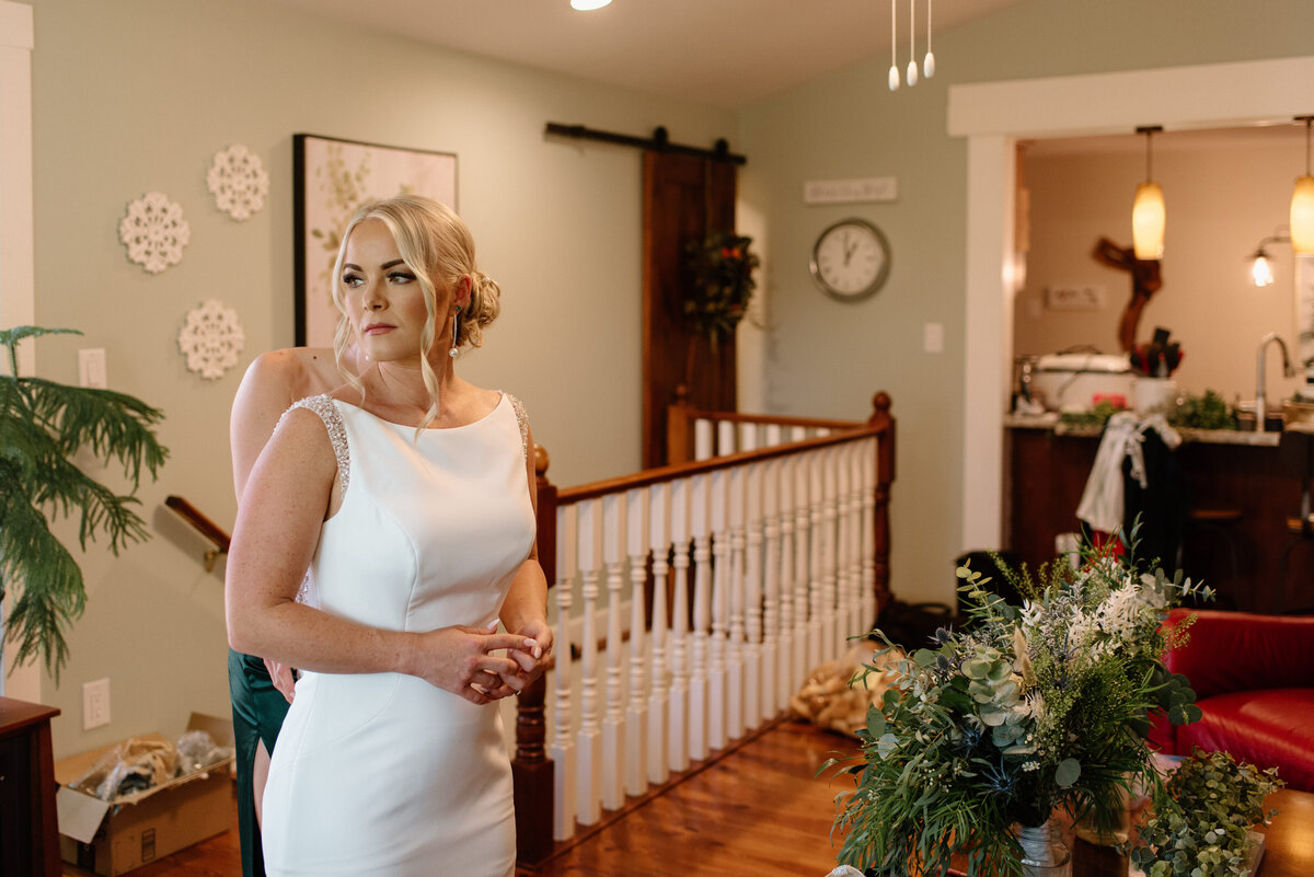 sister helping bride button up dress