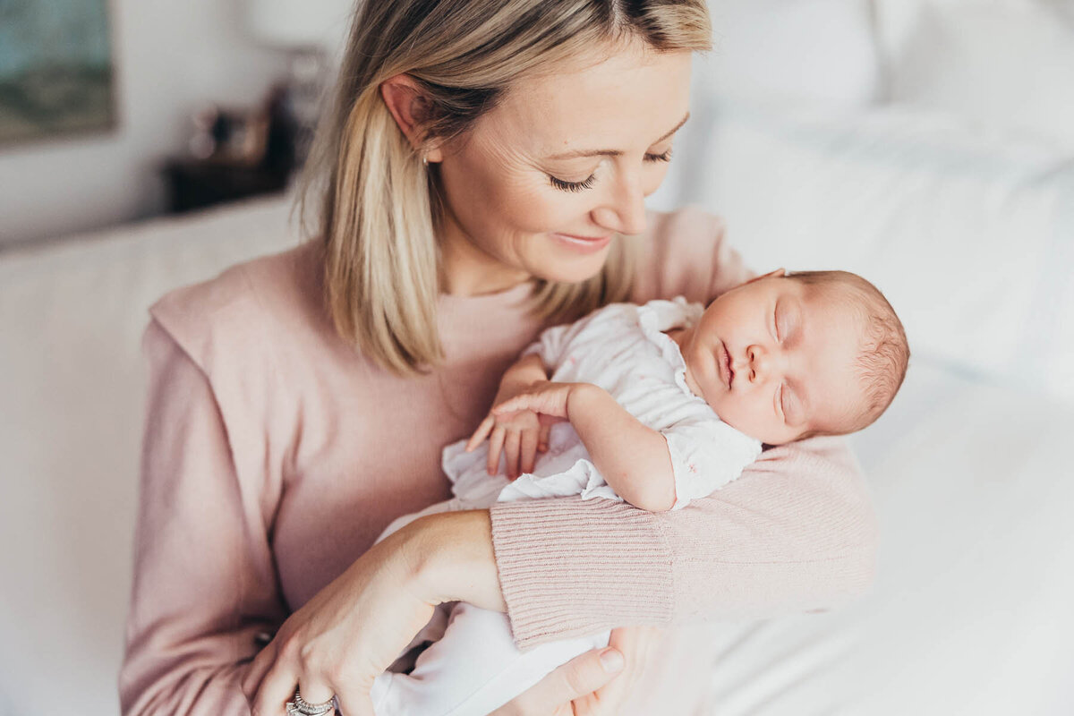 a mother holds her newborn baby while looking at her lovingly