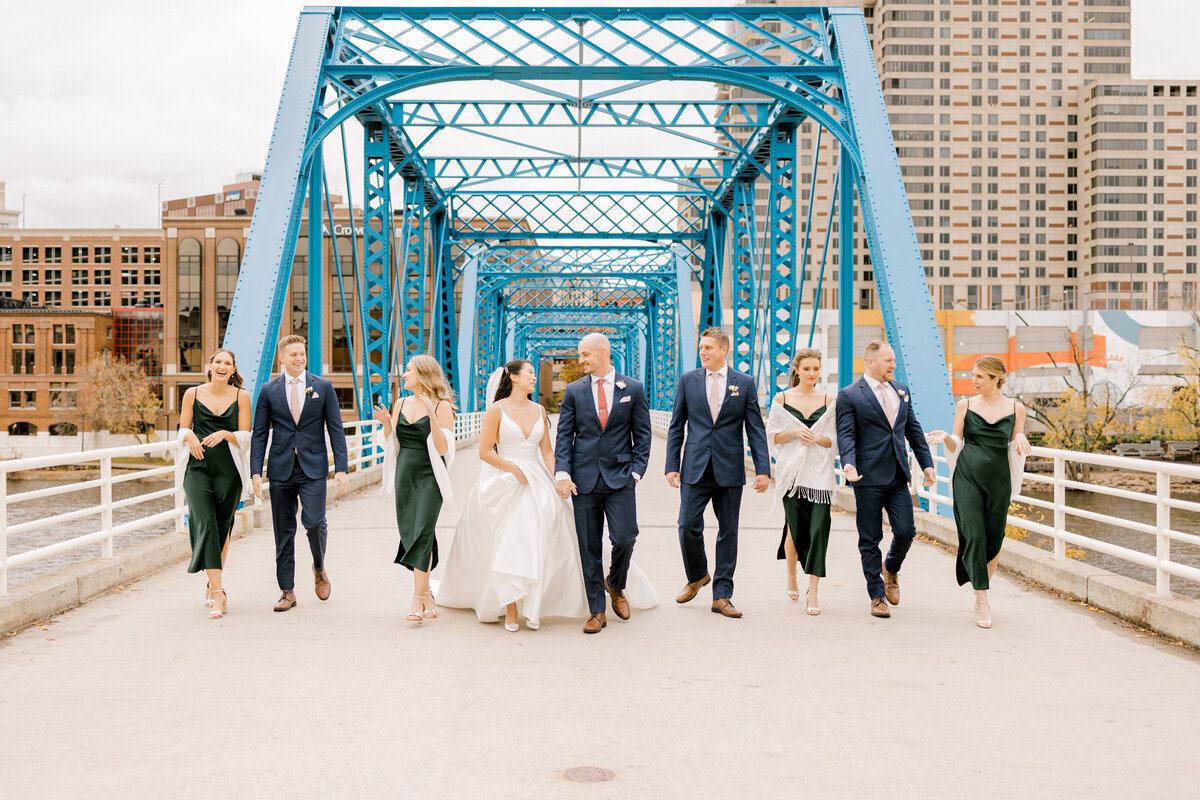 bridal party walking and talking on a blue bridge