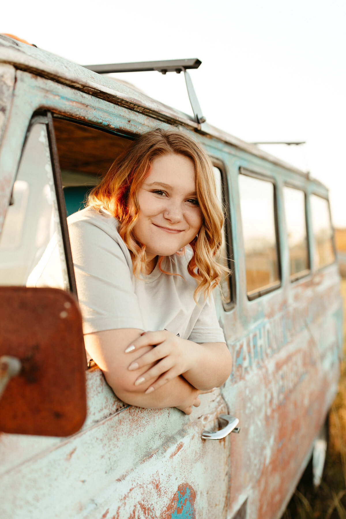 High school senior leaning out the window of an old vintage hippie van