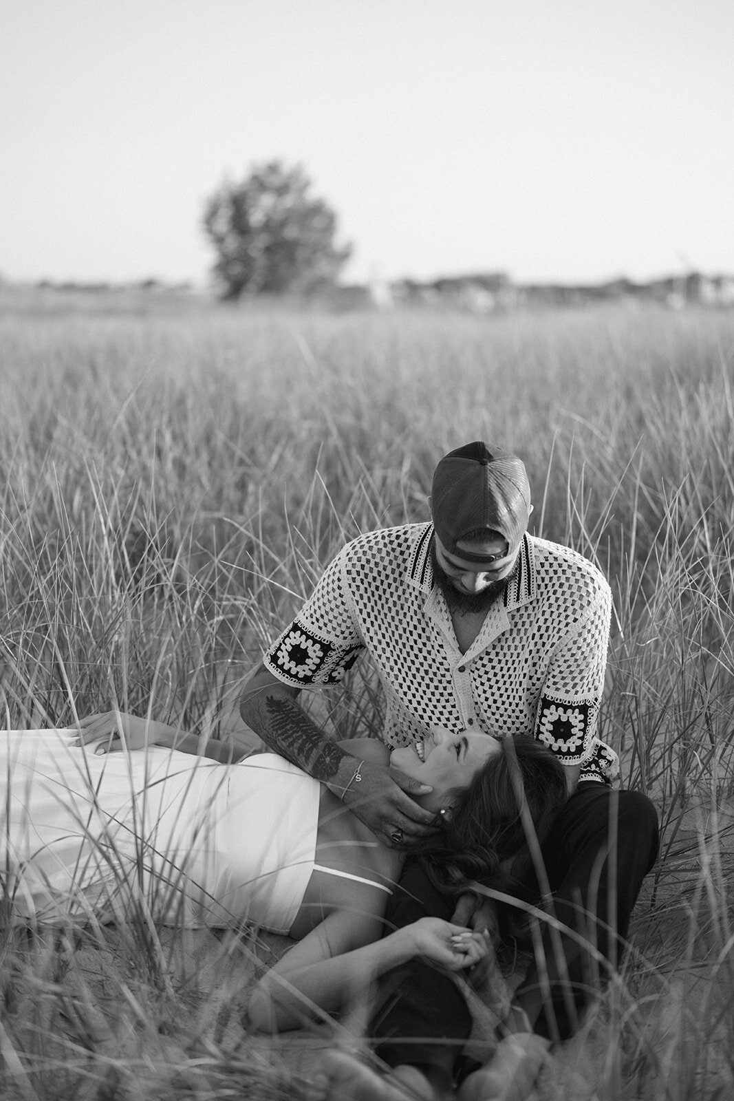 Black and white engagement photo of couple laying in the beach grass at New Buffalo Beach