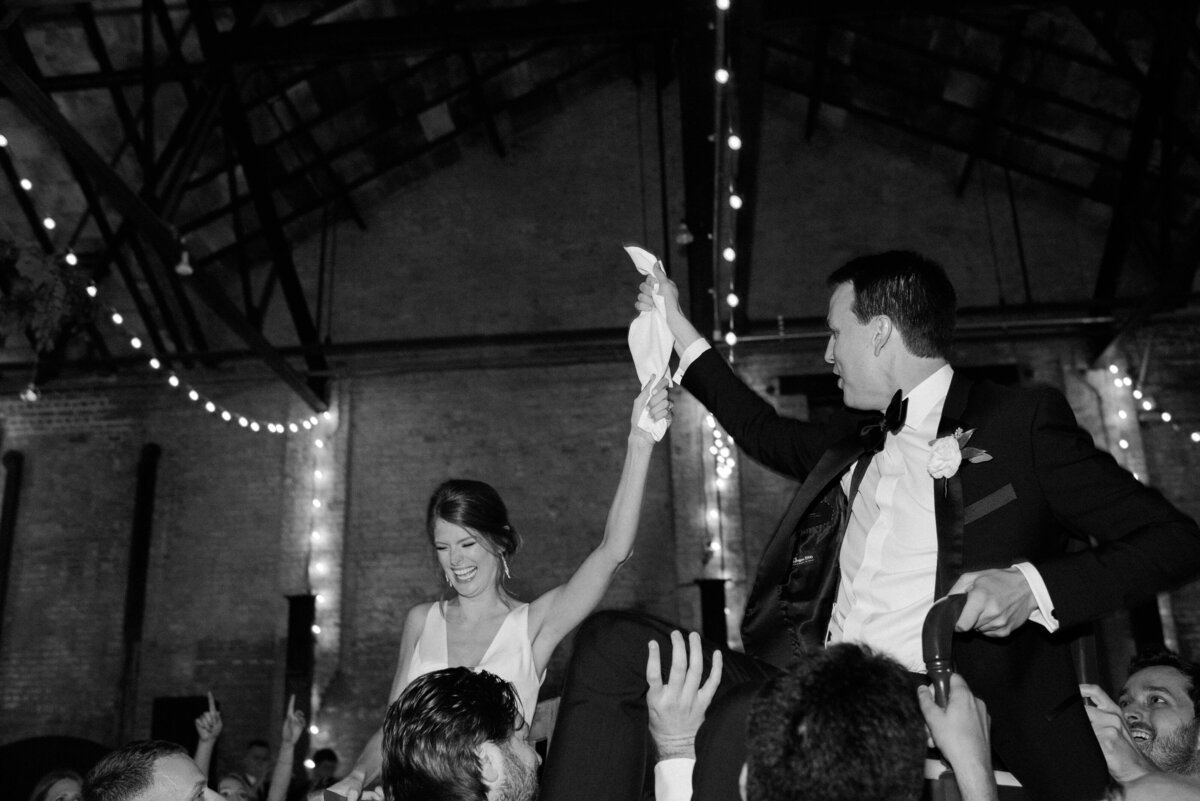 A couple celebrates as friends and family hold them
