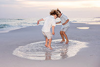little boys jumping in puddle of water at beach 30a