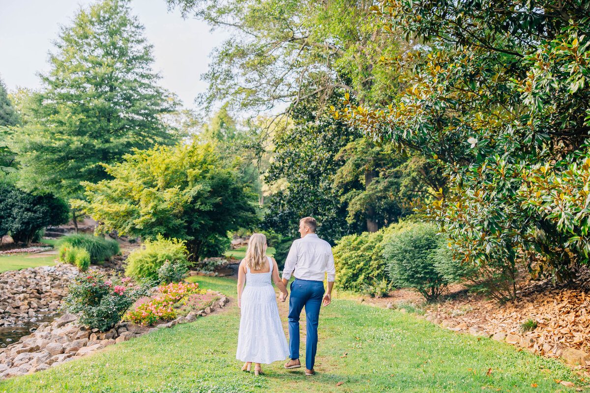 couple walking hand in hand with white dress on and navy pants