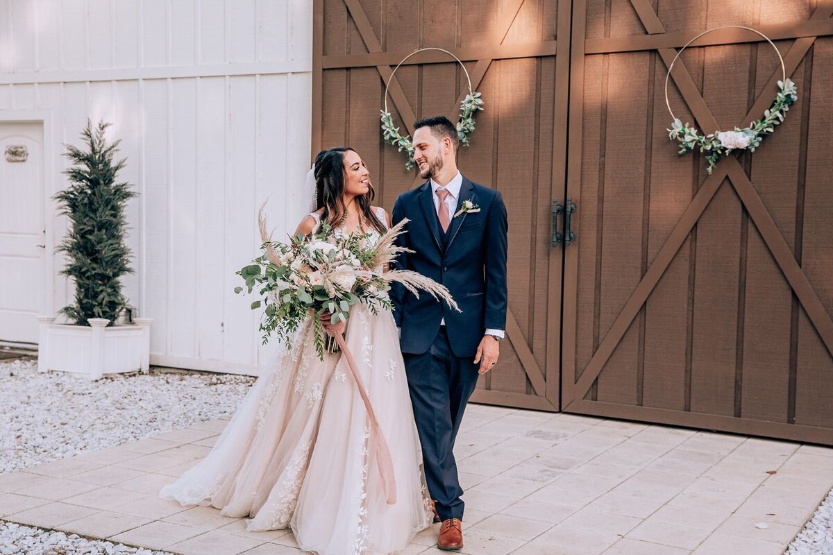 bride and groom walking in front of barn doors