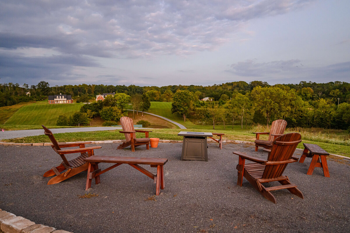 A cozy firepit surrounded by Adirondack chairs overlooking the rolling hills and countryside at Willow and Stone Events, located near Charlotte, NC.