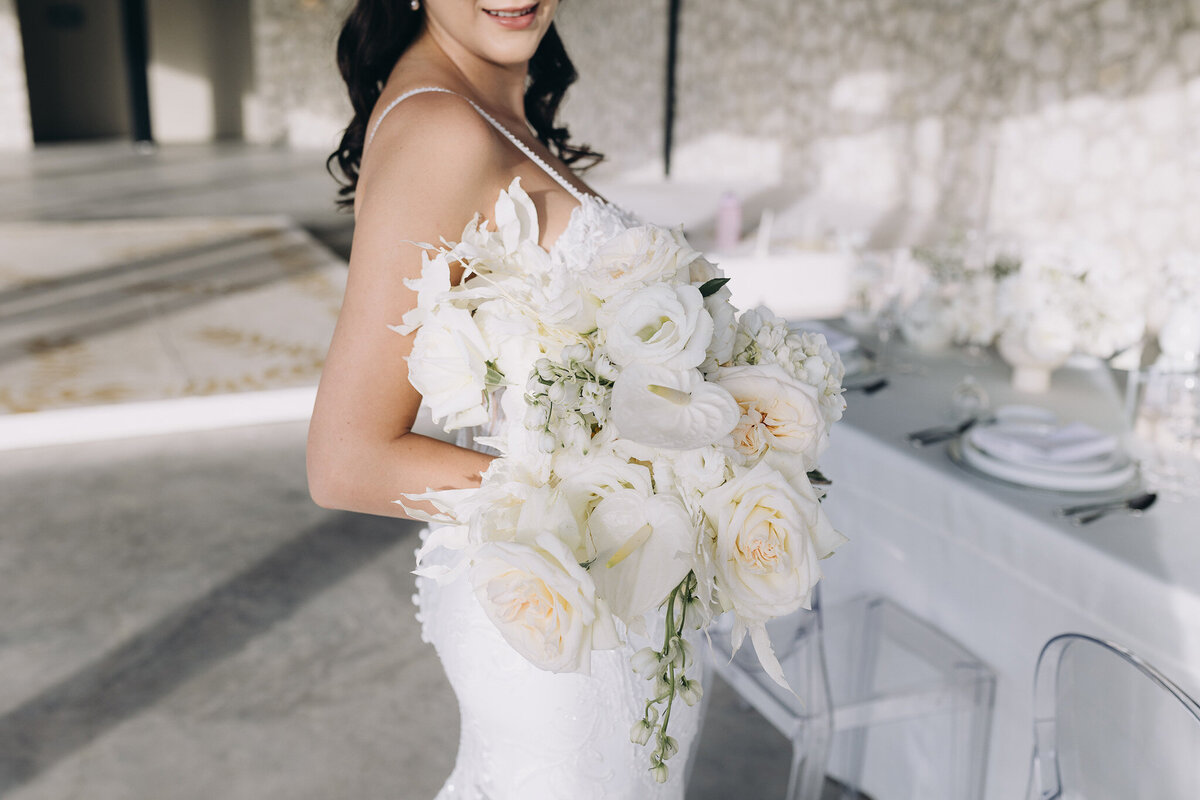 Bride in all-white gown holding ivory rose bouquet at White Whisper luxury wedding in Tuscany