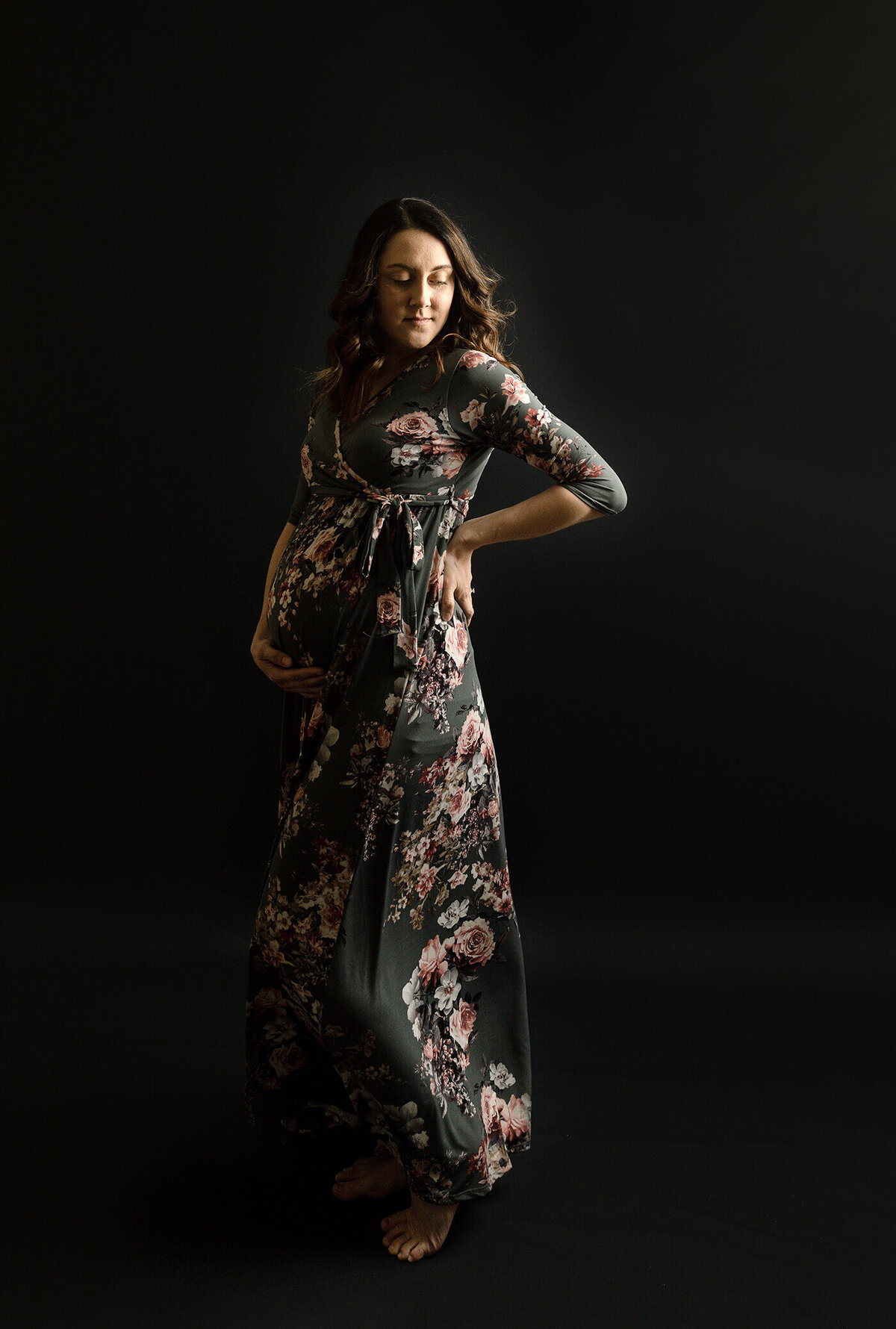 Pregnant Mom in a floral dress with black background.